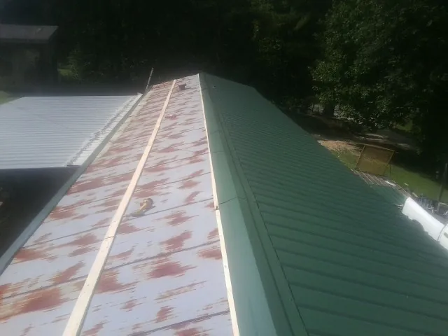 Old rusted panels beside newly installed green metal roofing — Wind Damage Roof Repair by Roofing Brothers in Charlestown